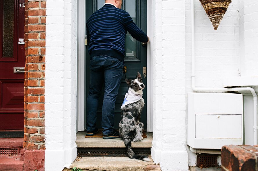 Man with Battersea dog at a front door